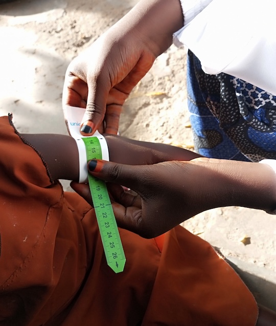 Adult measures a child's arm